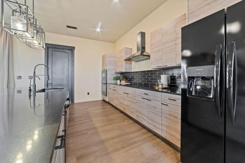 a kitchen with a black refrigerator and wooden floors at The Highlander - Luxe Hot Tub Firepit Views in Big Water
