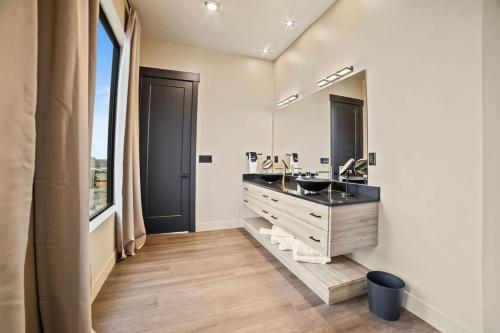 a bathroom with two sinks and a large mirror at The Highlander - Luxe Hot Tub Firepit Views in Big Water
