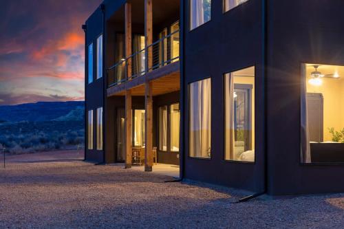 a building with windows and a sunset in the background at The Highlander - Luxe Hot Tub Firepit Views in Big Water