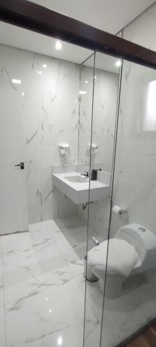 a white bathroom with a toilet and a sink at Hotel Chalés Capitanias in Águas de Lindóia