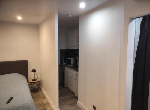 Cette petite chambre comprend un lit et une cuisine. dans l'établissement Studio Plain pied avec terrasse couverte 20m wifi et smart tv, à Hérin