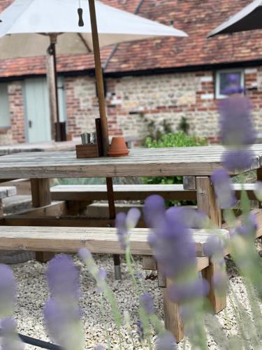 a picnic table with purple flowers and an umbrella at The Bath Arms Shearwater in Warminster
