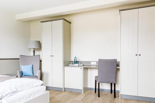 a bedroom with a bed and a desk and chairs at Hotel Klein Amsterdam in Friedrichstadt