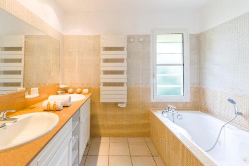 モリエ・エ・マーにあるLagrange Vacances La Clairière aux Chevreuilsのバスルーム(洗面台2台、バスタブ付)、窓が備わります。