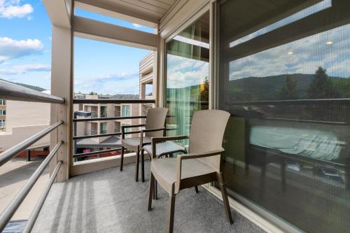 a balcony with chairs and a table and a large window at The Christie Lodge – All Suite Property Vail Valley/Beaver Creek in Avon