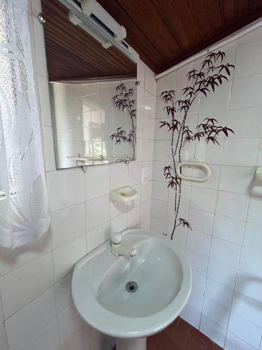 a white bathroom with a sink and a mirror at Suíte na casa Vida Mansa in Miguel Pereira