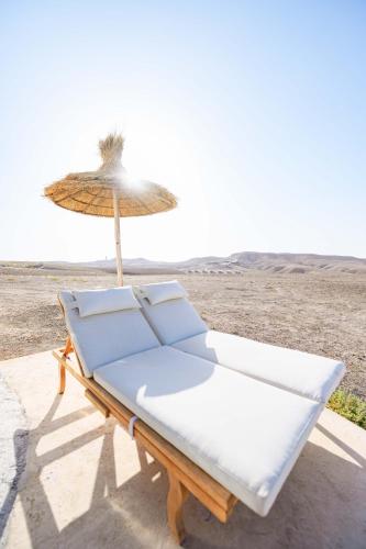 a bench with an umbrella on the beach at The Orion Dome in El Karia