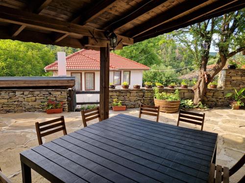 a wooden table and chairs on a patio at Къщи за гости "Зелената долина" in Dalbok-Dol