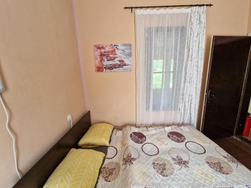 a small bedroom with a bed and a window at Къщи за гости "Зелената долина" in Dalbok-Dol