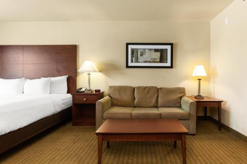 a hotel room with a bed and a couch at Cobblestone Hotel & Suites - Knoxville in Knoxville