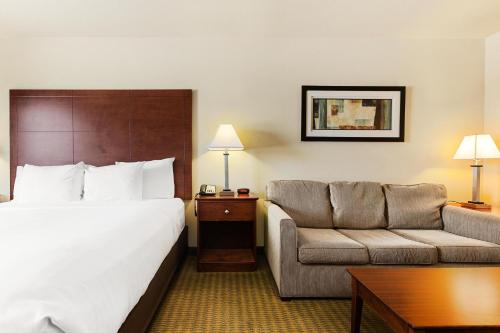 a hotel room with a bed and a couch at Cobblestone Hotel & Suites - Knoxville in Knoxville