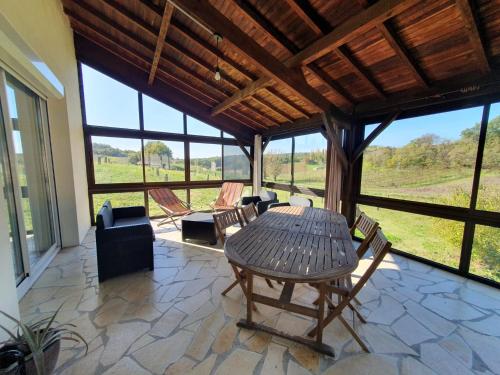 a dining room with a table and chairs and windows at Ferme de la felicità in Montbarla