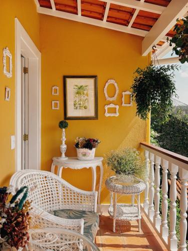 a porch with white wicker chairs and a yellow wall at La Belle Provence in Itaipava