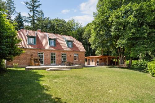 ein großes Backsteinhaus mit einem Rasenhof in der Unterkunft GUT KLETKAMP "Försterei" - Freistehendes Backsteinhaus mit 4 Schlafzimmern ruhig am Waldrand gelegen I Kamin I Garten & Terrasse I 15 Min zur Ostsee I 3 Bäder I Küche I Parkplatz I WLAN in Kletkamp
