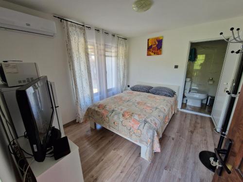 a bedroom with a bed and a tv in it at Къщи за гости "Зелената долина" in Dalbok-Dol