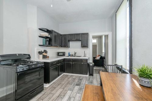 a kitchen with black cabinets and a wooden table at Chic Modern Gem with Style in Cincinnati