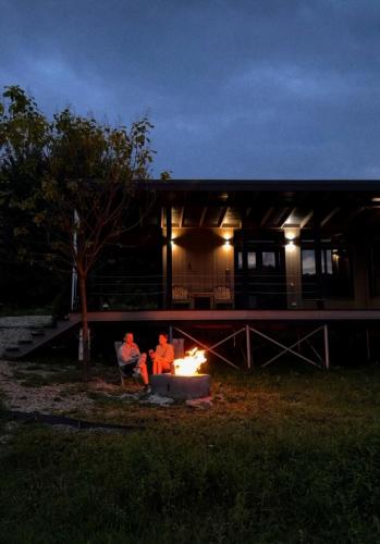 two people sitting around a fire in front of a building at Mahiya Vitriv in Staryy Sambor
