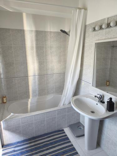 a bathroom with a white tub and a sink at Casa da Praça - Obidos Country Residence in Amoreira