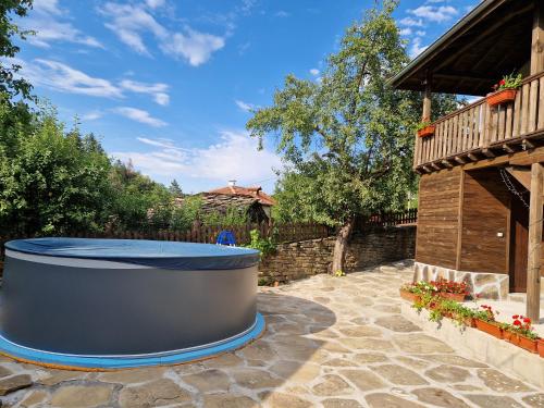 a large hot tub sitting on a stone patio at Къщи за гости "Зелената долина" in Dalbok-Dol