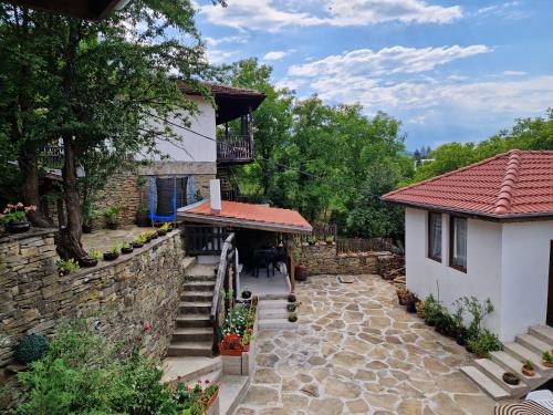 a house with a stone wall and a patio at Къщи за гости "Зелената долина" in Dalbok-Dol