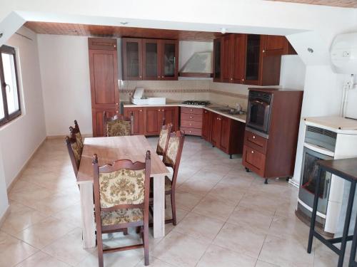 une cuisine avec des armoires en bois et une table et des chaises dans l'établissement Vila cu 3 Dormitoare cu Acces la Lac, à Gheboieni