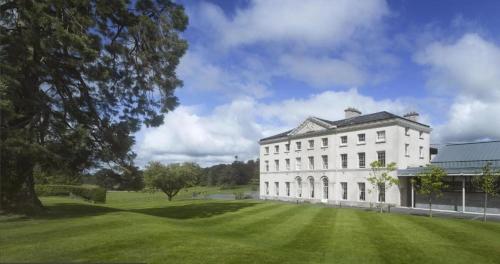 a large white building with a large grass field at Cois na hÉirne - Log Cabin I Lake View I Hot Tub in Belturbet