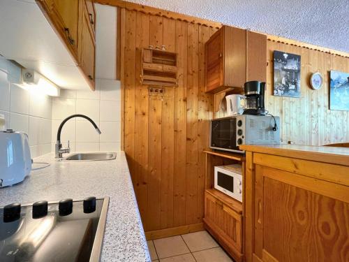 une cuisine avec des armoires en bois et un évier dans l'établissement Appartement ski aux pieds, 6 pers, balcon Sud-Ouest, animaux acceptés - Les Ménuires - FR-1-452-97, aux Menuires