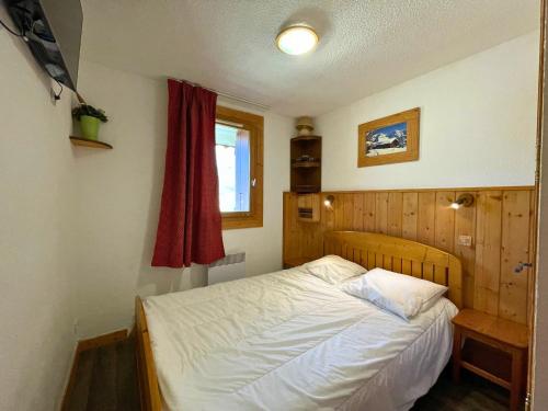 - une petite chambre avec un lit et un rideau rouge dans l'établissement Appartement ski aux pieds, 6 pers, balcon Sud-Ouest, animaux acceptés - Les Ménuires - FR-1-452-97, aux Menuires