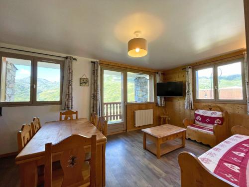 un salon avec une table, des chaises et des fenêtres dans l'établissement Appartement lumineux 6 pers, ski aux pieds, balcon sud-ouest, Les Menuires, 3 flocons 