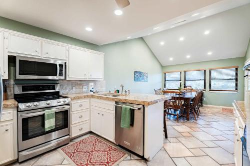 a kitchen with white cabinets and a dining room with a table at Waterfront Home on Lake Travis in Lakeway
