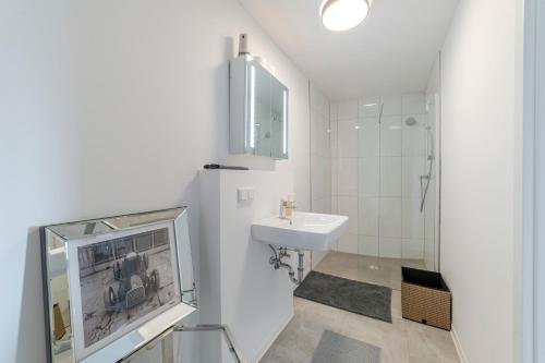 a white bathroom with a sink and a mirror at Bunker Loft Messe Essen Self Check-in in Essen