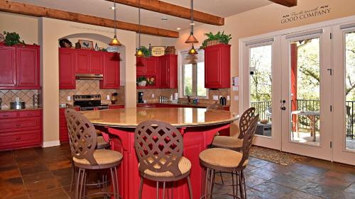 a kitchen with red cabinets and a large island with chairs at Pet-Friendly Oasis in Gated Community in Spicewood