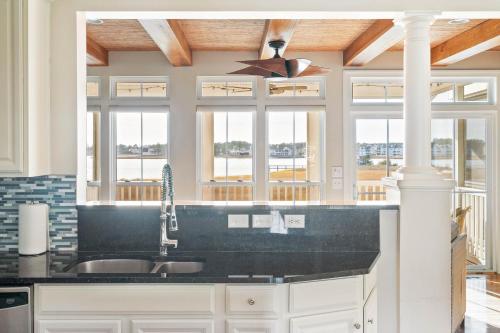 a kitchen with a black counter top and windows at Hidden Paradise - Coastal Views in Ocean View