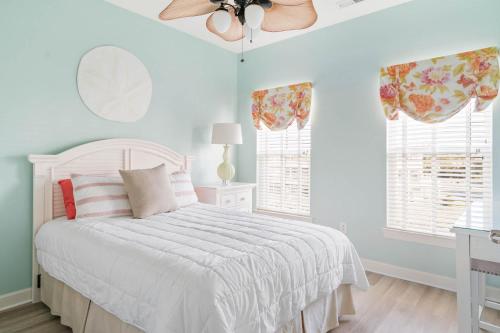 a bedroom with a white bed with a ceiling fan at Hidden Paradise - Coastal Views in Ocean View