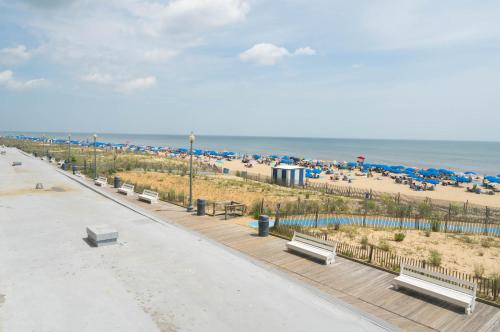 a beach with benches and umbrellas and the ocean at Seaside Star - On The Boardwalk in Rehoboth Beach