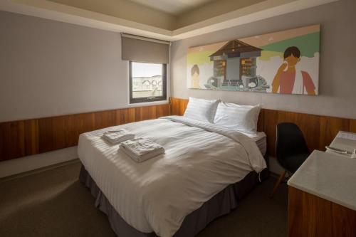 a hotel room with a large bed and a painting on the wall at Meci Hotel in Hualien City
