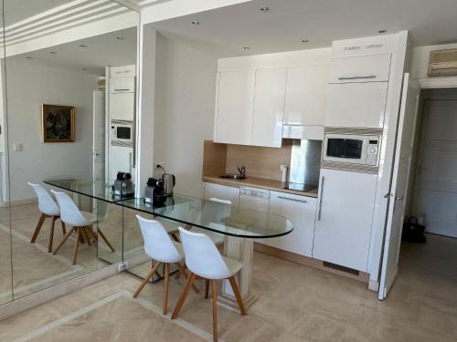 une cuisine avec une table en verre et des appareils électroménagers blancs dans l'établissement PALAIS MIRAMAR 65 BD DE LA CROISETTE CANNES, à Cannes