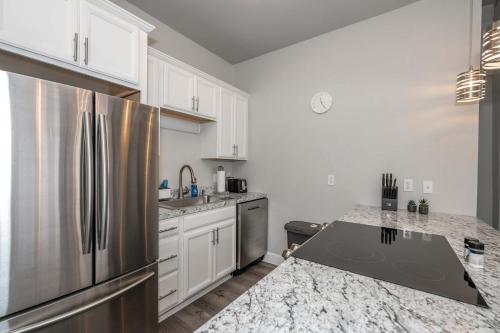 a kitchen with a stainless steel refrigerator and white cabinets at The Heart of Madison Suites in Covington