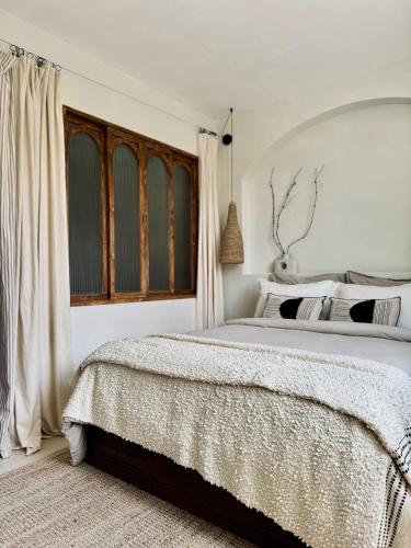 a white bedroom with a large bed and a window at VINEÀ Suite in Angé