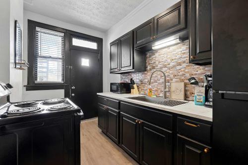 a kitchen with black cabinets and a sink and a stove at Merion Village Residences 1166 in Columbus