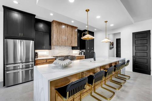 a kitchen with black cabinets and a white island with chairs at Lakefront Stay for 16 with Pool Dock & Game Room in Granite Shoals