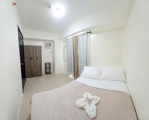 a bedroom with a white bed with a bow on it at Cozy Nook in the City in Manila