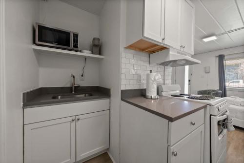 a white kitchen with a sink and a microwave at Chic City Retreat 99 For 2 in Columbus