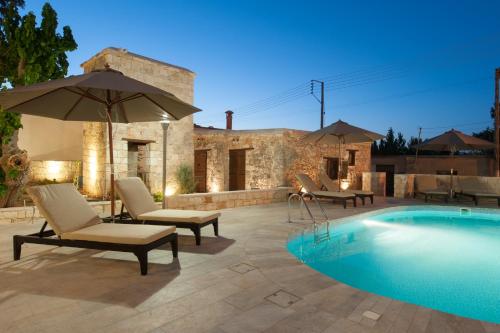 a pool with chairs and an umbrella next to a building at Ktima 1937 Kannides in Drousha