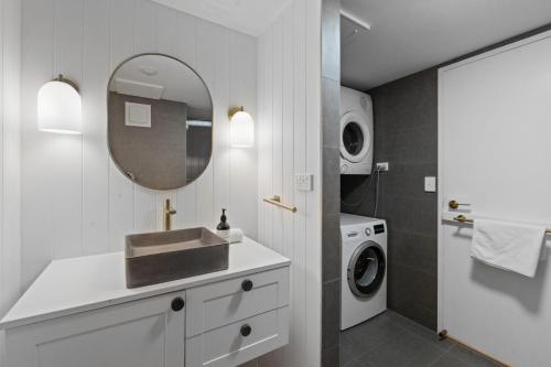 a bathroom with a sink and a washing machine at The Beachside - Fully Renovated 2BR unit with Parking Pool Tennis next to beach and tram in Gold Coast
