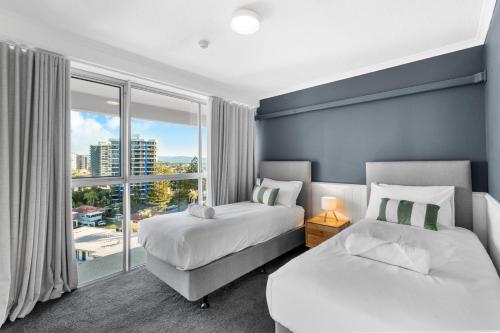 a bedroom with two beds and a large window at The Beachside - Fully Renovated 2BR unit with Parking Pool Tennis next to beach and tram in Gold Coast