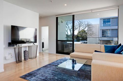 a living room with a couch and a tv at Central Modern Duplex Home near Cornwall Park in Auckland