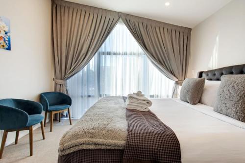 a bedroom with a bed with two chairs and a large window at Central Modern Duplex Home near Cornwall Park in Auckland