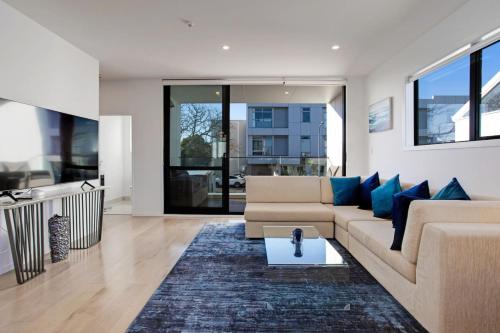 a living room with a couch and blue pillows at Central Modern Duplex Home near Cornwall Park in Auckland