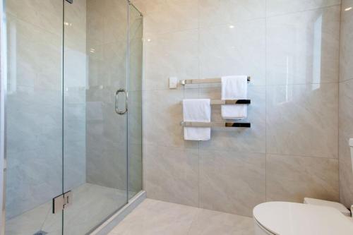 a bathroom with a glass shower with a toilet and towels at Central Modern Duplex Home near Cornwall Park in Auckland